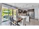 View of the kitchen and dining area with an outdoor patio, dark cabinets, stainless appliances and modern lighting at 8120 Soldierwood St, Winter Garden, FL 34787