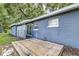 Home exterior with wooden deck, glass block accent, and blue siding surrounded by trees at 906 E Lowell St, Lakeland, FL 33805