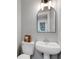 A quaint powder room features a pedestal sink, toilet, and a decorative mirror for added charm at 1018 E Highland Dr, Lakeland, FL 33813