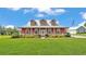 Charming two-story home with a metal roof, a lovely front porch, and lush landscaping, creating a welcoming facade at 1044 Timbers Dr, Fort Meade, FL 33841