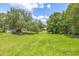 Expansive grassy lot featuring mature trees and a glimpse of the home in the distance at 1102 Berkley Ln, Winter Haven, FL 33880