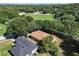 Aerial view of a home with a brown roof surrounded by lush green trees and a green field at 1125 Blackjack Ridge St, Minneola, FL 34715