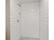 Close-up of a white subway tile shower featuring hexagon tile flooring and a built-in shower niche at 1125 Blackjack Ridge St, Minneola, FL 34715