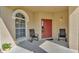 Inviting front porch with seating area, arched window, and a red front door at 141 Minniehaha Cir, Haines City, FL 33844