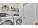 Bright laundry room featuring a modern washer and dryer, storage shelves, and a door at 141 Minniehaha Cir, Haines City, FL 33844