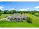 Aerial view captures a serene estate with a large house, a pond, green fields, and mature trees at 15195 Angus Rd, Polk City, FL 33868