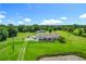 Aerial view of a property featuring a well-maintained lawn, a pond, and multiple buildings at 15195 Angus Rd, Polk City, FL 33868