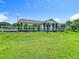Exterior of home with a well-manicured lawn, white fence, and elegant columns, creating a welcoming atmosphere at 15195 Angus Rd, Polk City, FL 33868