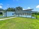 The exterior of this farmhouse is enhanced by a lush lawn and mature trees and landscaping at 15195 Angus Rd, Polk City, FL 33868