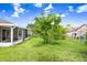 A fenced backyard with a lawn, play structure, mature trees, and screened in patio at 169 Birmingham Dr, Kissimmee, FL 34758