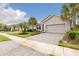 Charming single-Gathering home featuring a well-manicured lawn, paved driveway, and lush landscaping with palm trees at 180 Azure Mist Way, Daytona Beach, FL 32124