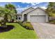 Charming single-story home with lush landscaping, brick driveway, and gray exterior at 180 Azure Mist Way, Daytona Beach, FL 32124