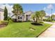 Beautifully landscaped front yard with lush green lawn, elegant flower beds, and stately palm trees enhancing curb appeal at 180 Azure Mist Way, Daytona Beach, FL 32124