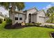 Landscaped front yard featuring a well-maintained lawn, decorative plants and a graceful palm tree at 180 Azure Mist Way, Daytona Beach, FL 32124