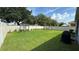 Large grassy backyard featuring a white fence, shade trees, and an area for outdoor dining at 2169 Rush Bay Way, Orlando, FL 32824