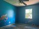 Bedroom with vibrant blue walls, ceiling fan, and bright window; awaiting transformation for stylish comfort at 2250 Maple Hill Dr, Lakeland, FL 33811