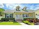 Inviting front porch of a yellow house featuring classic columns, black sconces, and colorful landscaping at 2264 Palmview E Cir, Auburndale, FL 33823