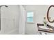 Bright white bathroom features a shower-tub combination, a window, and a round mirror at 236 E Seminole Ave, Lake Wales, FL 33853