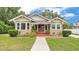 Charming bungalow with red front porch, walkway and well-manicured lawn under a partly cloudy blue sky at 236 E Seminole Ave, Lake Wales, FL 33853