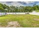 Expansive backyard with lush green grass, a pristine white fence, play equipment, and mature trees for privacy at 2443 Delrose E Dr, Lakeland, FL 33805