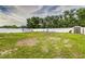 Large backyard featuring a white fence, a play area, ample space for outdoor activities, and mature trees in the background at 2443 Delrose E Dr, Lakeland, FL 33805