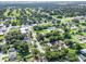 Wide aerial shot displays a neighborhood with houses interspersed among lush green trees and nearby golf course at 405 S 7Th Ave, Bartow, FL 33830