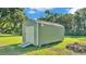Exterior of a light gray shed with a roll-up door in the backyard at 6533 Angus Dr, Lakeland, FL 33810