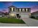 Charming two-story home at dusk with manicured lawn, gray siding, dark green shutters, and an attached two-car garage at 7116 Cruz Ct, Lakeland, FL 33813