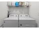 Bright laundry room with white washer, dryer, and wire rack shelving with cleaning supplies at 943 Grandin St, Davenport, FL 33837