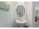 Charming powder room features a pedestal sink, decorative mirror, and serene blue walls at 943 Grandin St, Davenport, FL 33837