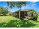Backyard view showcasing the screened-in patio, lush lawn, and mature trees, ideal for outdoor enjoyment at 961 Christina Chase Dr, Lakeland, FL 33813
