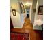 Long hallway with decorative paintings, wood floors and a red patterned area rug at 1216 W Lake Buckeye Dr, Winter Haven, FL 33881