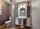 Bathroom featuring a pedestal sink, shelving, round mirror, and toilet at 1232 Fairlee St, Lakeland, FL 33813