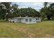 Single-story home boasting a spacious yard, mature trees, and a patio with colorful chairs at 21 Lake Ave, Winter Haven, FL 33880