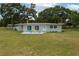 Charming single-story home featuring a spacious backyard with lush lawn and inviting patio with colorful chairs at 21 Lake Ave, Winter Haven, FL 33880