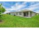 A backyard view shows the home's exterior with a green lawn and covered patio at 221 Hilltop Bloom Loop, Haines City, FL 33844