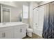 Bright bathroom featuring a white vanity, toilet, shower-tub combo with decorative curtain, and wood-look tile floor at 221 Hilltop Bloom Loop, Haines City, FL 33844
