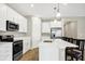 Modern kitchen with sleek white cabinetry, stainless steel appliances, and a quartz countertop breakfast bar at 221 Hilltop Bloom Loop, Haines City, FL 33844