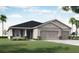 Charming single-Gathering home features a three-car garage, gray facade, and lush landscaping, creating inviting curb appeal at 2228 Summerlake Ct, Auburndale, FL 33823