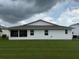 Home exterior featuring an enclosed patio, windows, white siding, and a lush green lawn at 2235 Grand Cypress Dr # 561, Lakeland, FL 33810