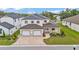 Aerial view of a two-story home featuring a three-car garage, a brick-paved driveway, and well-maintained landscaping at 2736 Sunrise Landing Ln, Lakeland, FL 33812