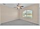 Bright bedroom featuring gray carpet, lighted ceiling fan, and a large window at 2812 Whitney St, Lakeland, FL 33813