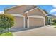 Spacious two-car garage with tan doors, white trim, and a concrete driveway, complemented by lush landscaping at 2812 Whitney St, Lakeland, FL 33813