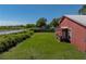 Expansive backyard with lush green grass, water view, and a charming barn-style building at 4230 Viola Rd, Lakeland, FL 33810