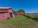 Spacious backyard with green lawn and a red barn-style building, perfect for outdoor activities at 4230 Viola Rd, Lakeland, FL 33810