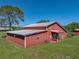 Side view of red barn-style home with a metal roof and well-maintained lawn at 4230 Viola Rd, Lakeland, FL 33810