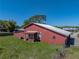 Side view of a red barn-style home with a metal roof and well-kept lawn at 4230 Viola Rd, Lakeland, FL 33810