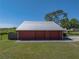 Exterior view of a red metal building with a large silver metal roof and a double-wide garage door at 4230 Viola Rd, Lakeland, FL 33810