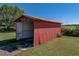 Exterior view of a red metal shed with an open bay and concrete floor at 4230 Viola Rd, Lakeland, FL 33810