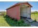 View of the red metal shed showing overgrown vegetation near the base at 4230 Viola Rd, Lakeland, FL 33810